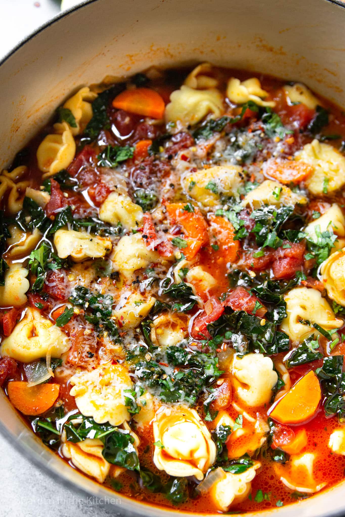 close up on vegetable tortellini soup in a large pot.