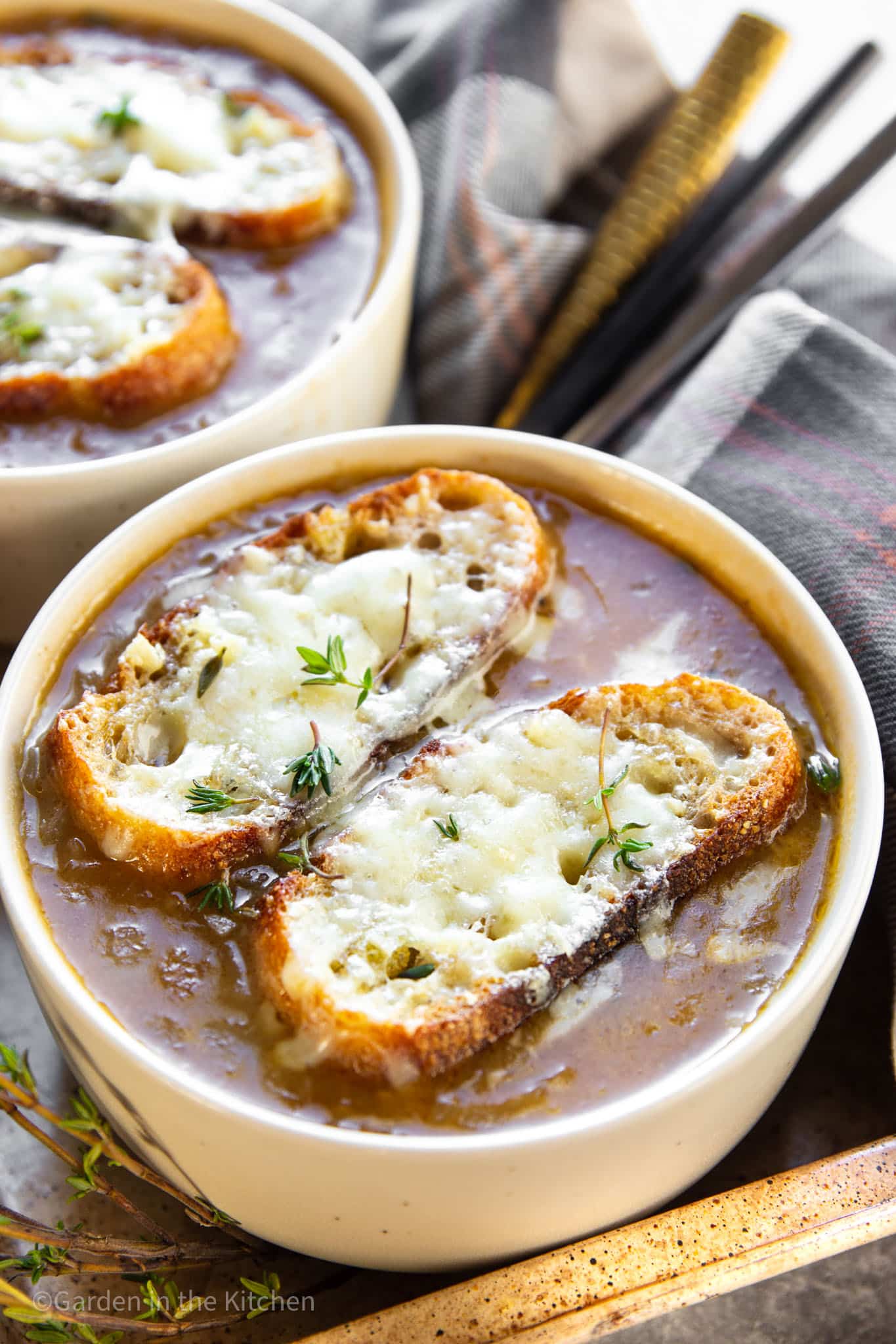 close up on a bowl of french onion soup topped with toasted bread and melted cheese.