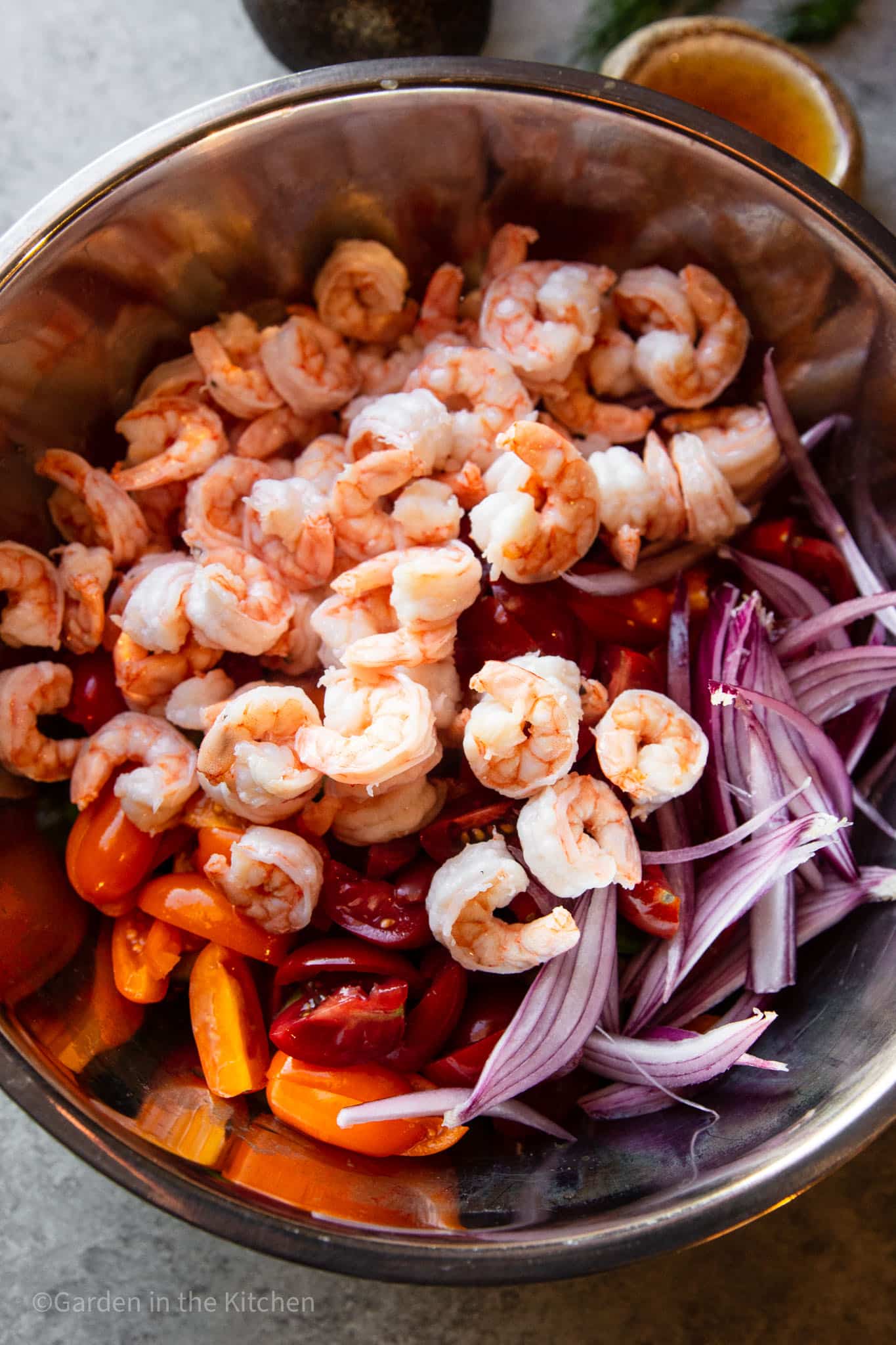 shrimp, chopped red onion, cucumbers, and tomatoes in a large metal bowl. 