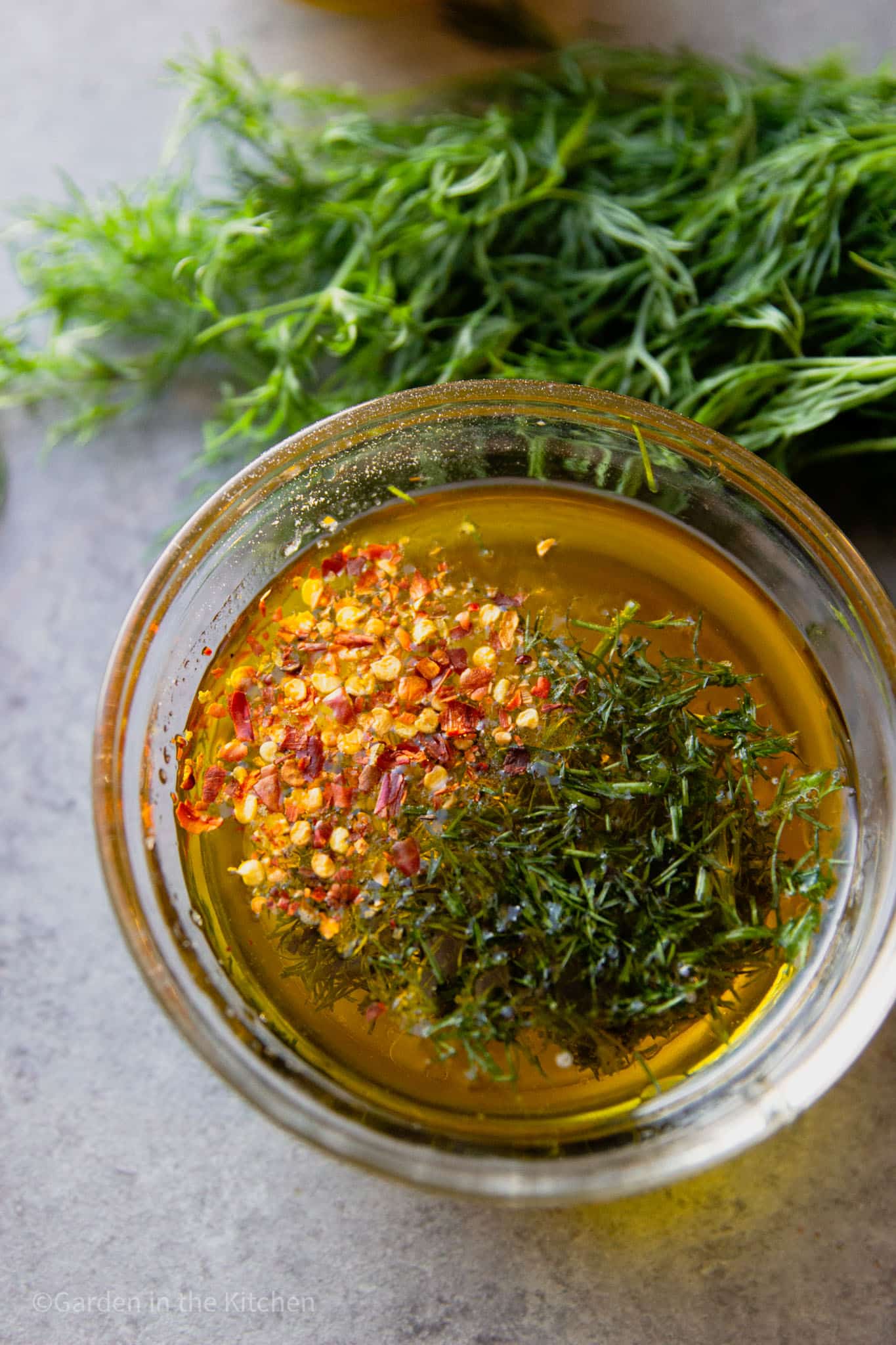 dill and red chili flakes in a glass bowl with olive oil and lemon juice.