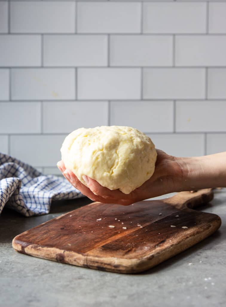 a hand holding a ball of dough.