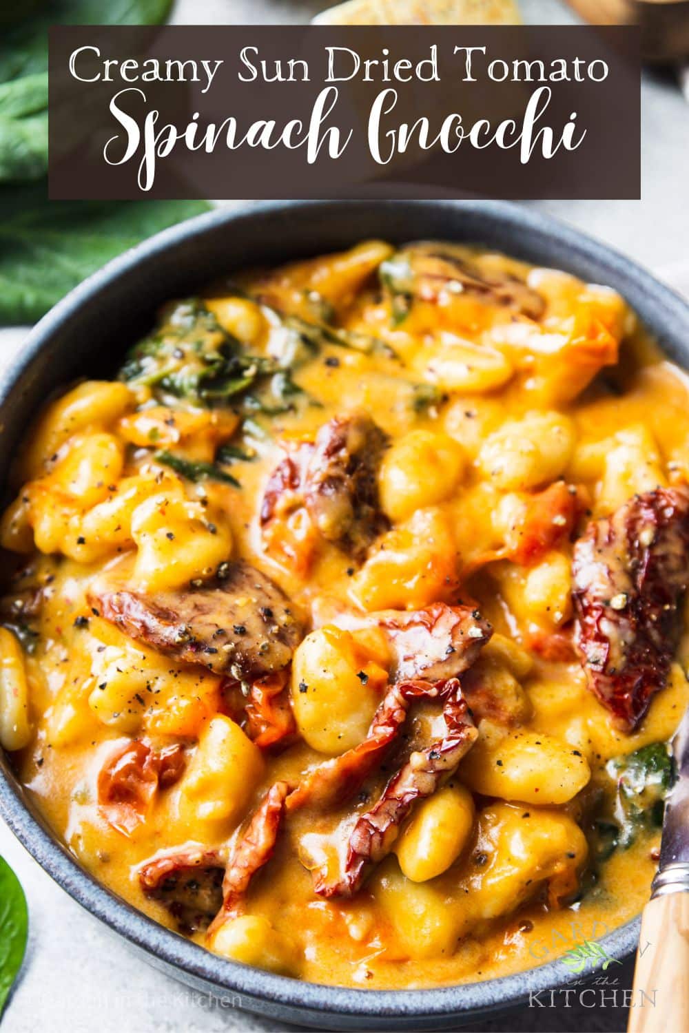 pinterest image of sun dried tomatoes and gnocchi in a cheesy, creamy sauce in a gray bowl.