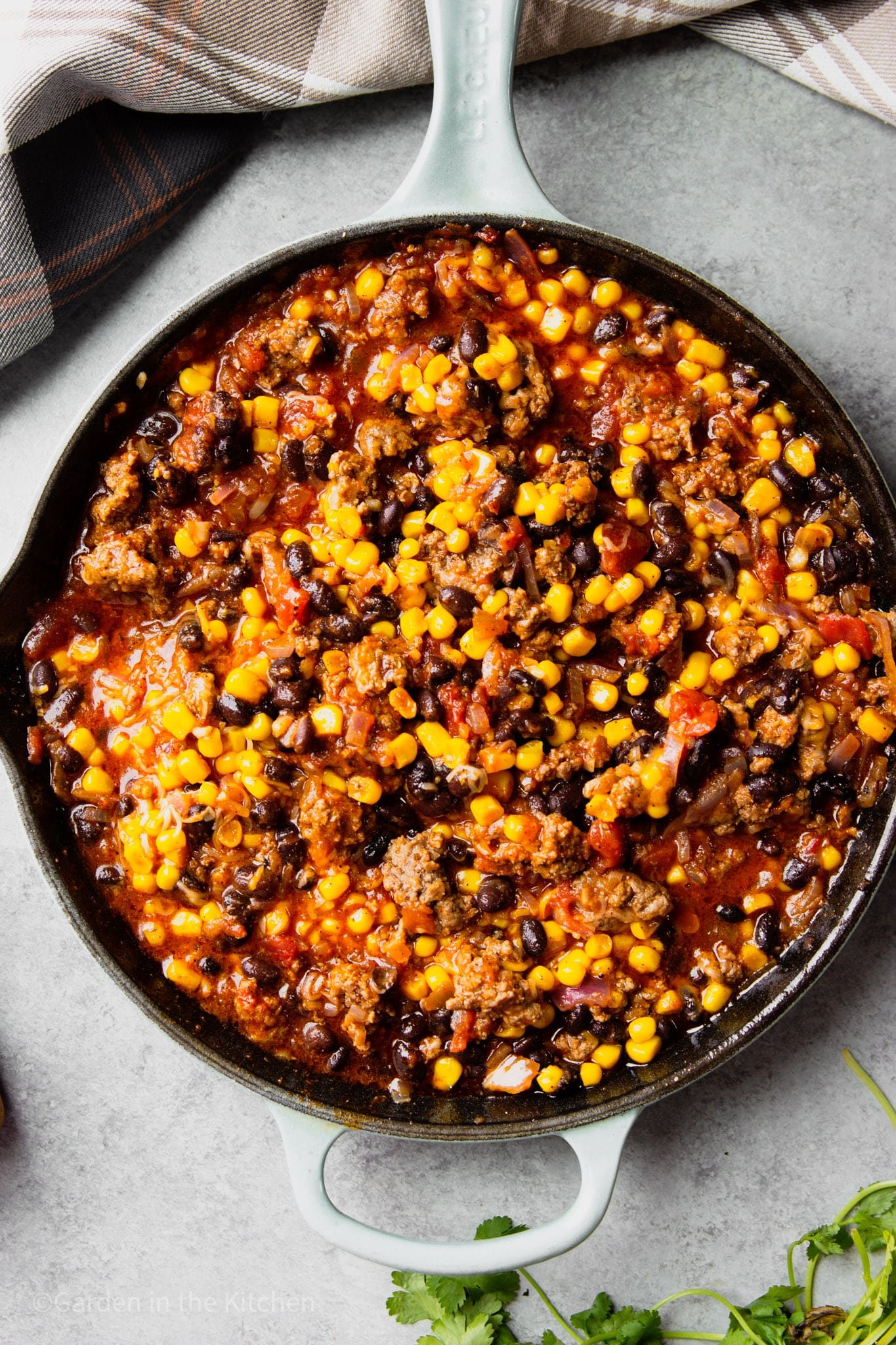 a mixture of cooked ground beef, corn, black beans, and salsa in a large black skillet.
