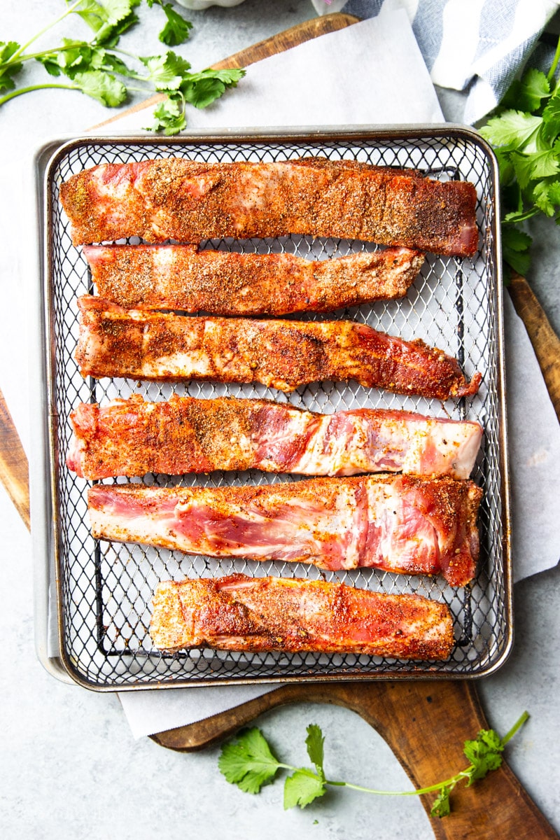 raw dry rubbed spare ribs on a metal baking sheet.