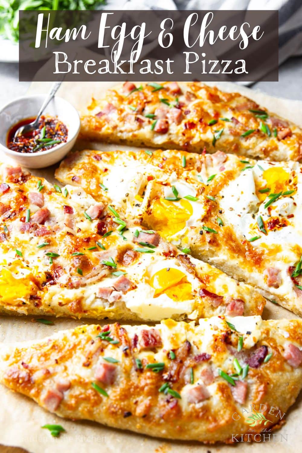 Sliced of breakfast pizza with eggs, bacon, ham and cheese. A pinch bowl with chili oil for garnishing. 