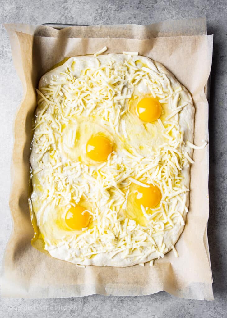 Raw pizza dough with raw eggs and cheese.