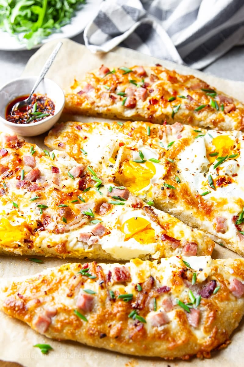 Breakfast pizza with eggs, ham and cheese. Chili oil for garnish.