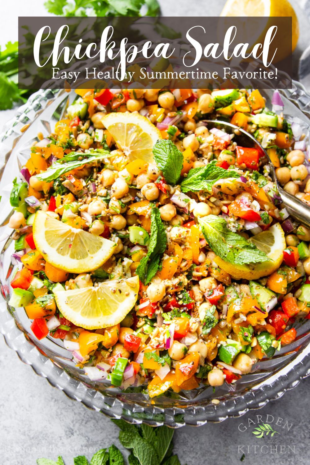 A big bowl of chickpea salad with a colorful variety of veggies. Vegan salad. Topped with lemon slices and mind. 