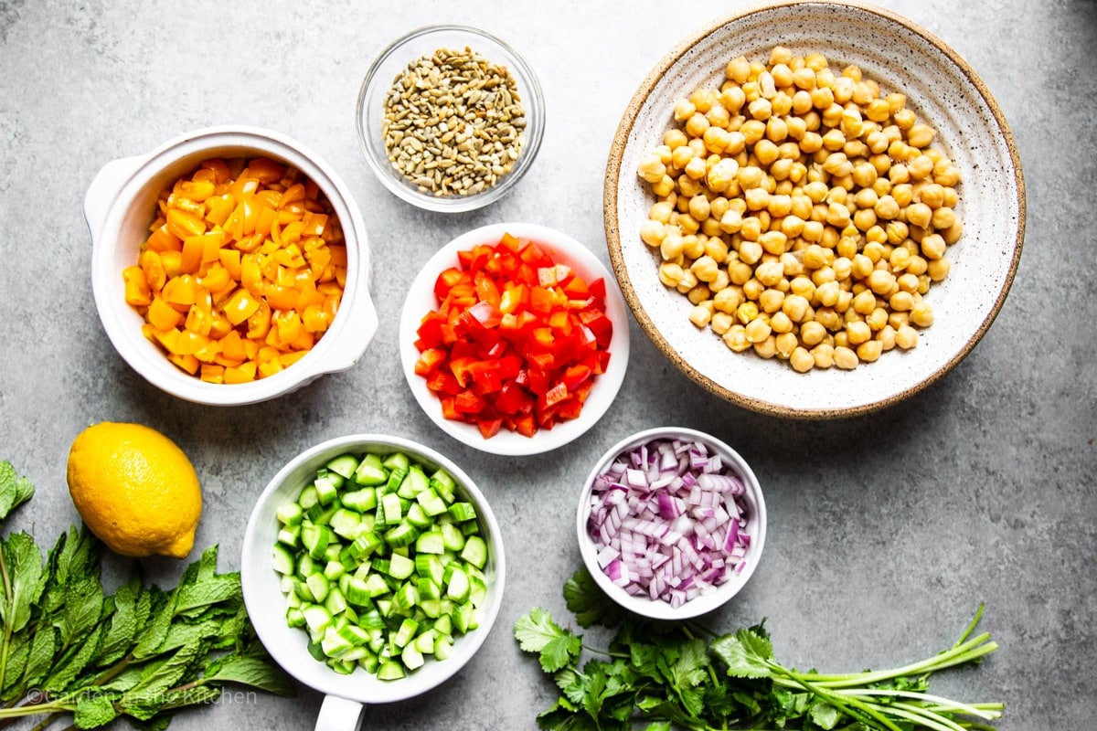 ingredients for a simple chickpea salad in individual white bowls.