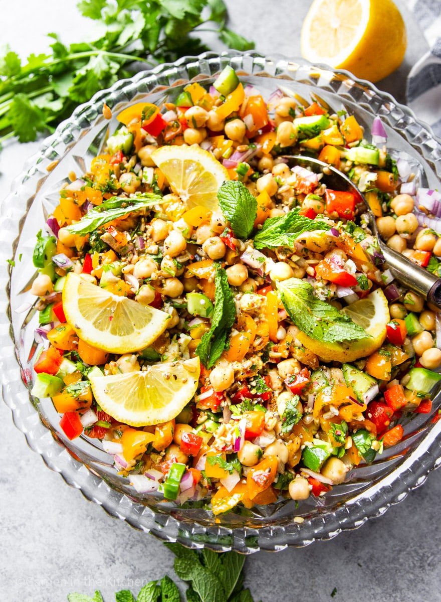lemon and mint-garnished chickpea and vegetable salad in a large glass bowl.