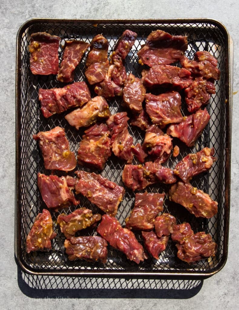 Marinated steak tips in the air fryer basket.