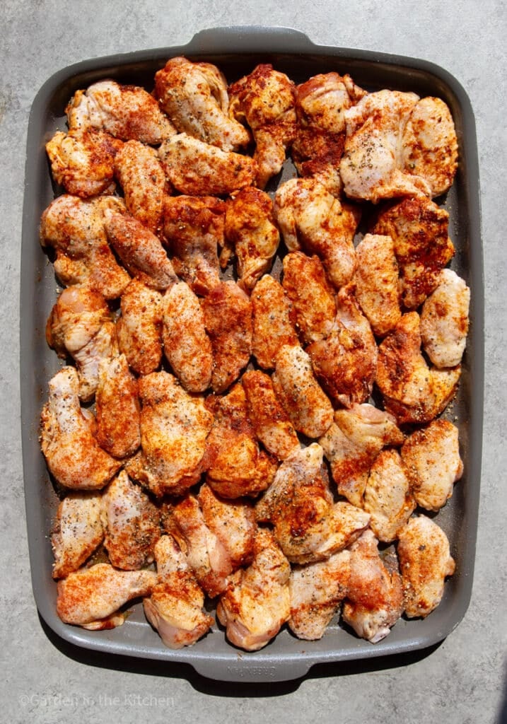 Chicken wings seasoned with paprika and garlic powder, on a sheet pan. 