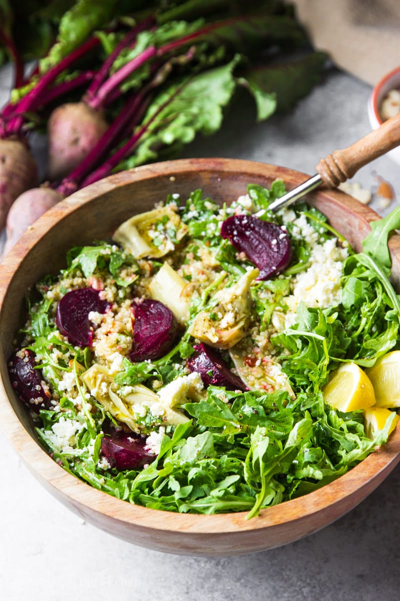 Quinoa salad with beets, arugula and feta cheese, served in a round wooden bowl. 