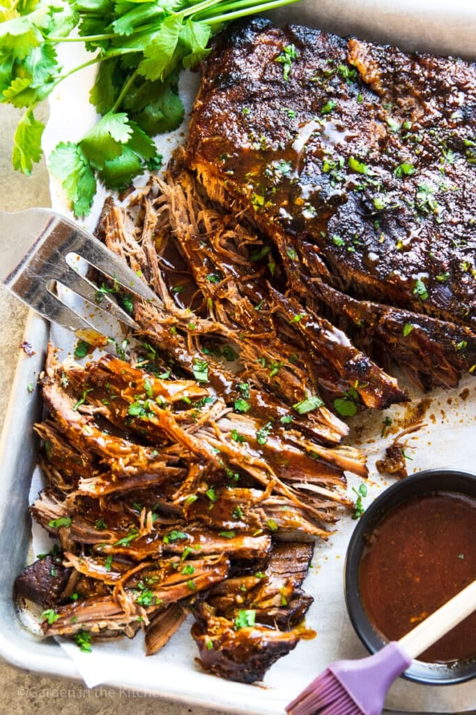 Cooked and shredded slow cooker brisket with barbeque sauce and cilantro.