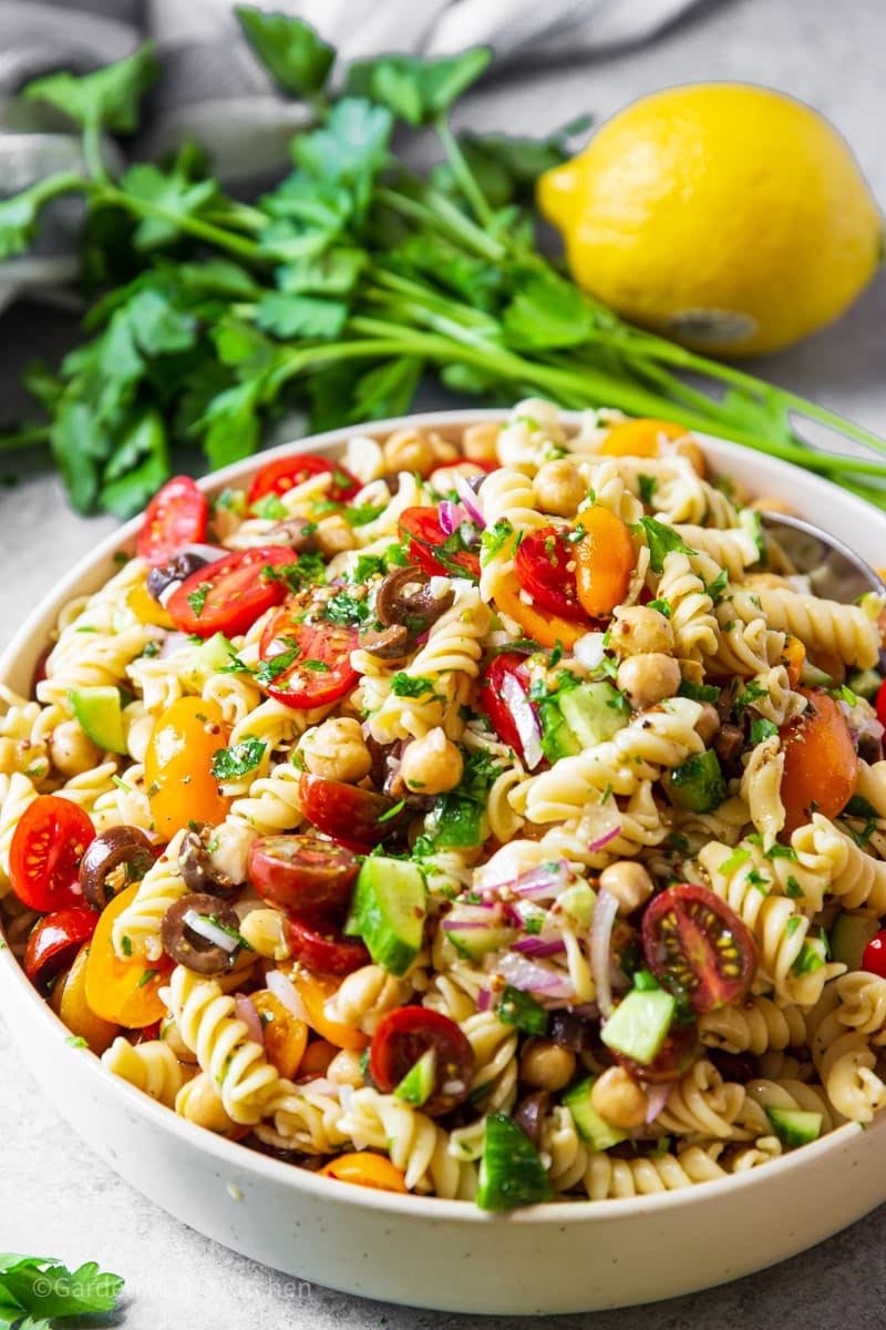 This tasty Mediterranean Chickpea Pasta Salad is chock full of protein for a hearty salad that eats like a meal.  Rotini pasta, chickpeas, cucumbers, black olives, and cherry tomatoes are tossed with an olive oil and lemon juice based dressing for a rainbow of color and flavor.