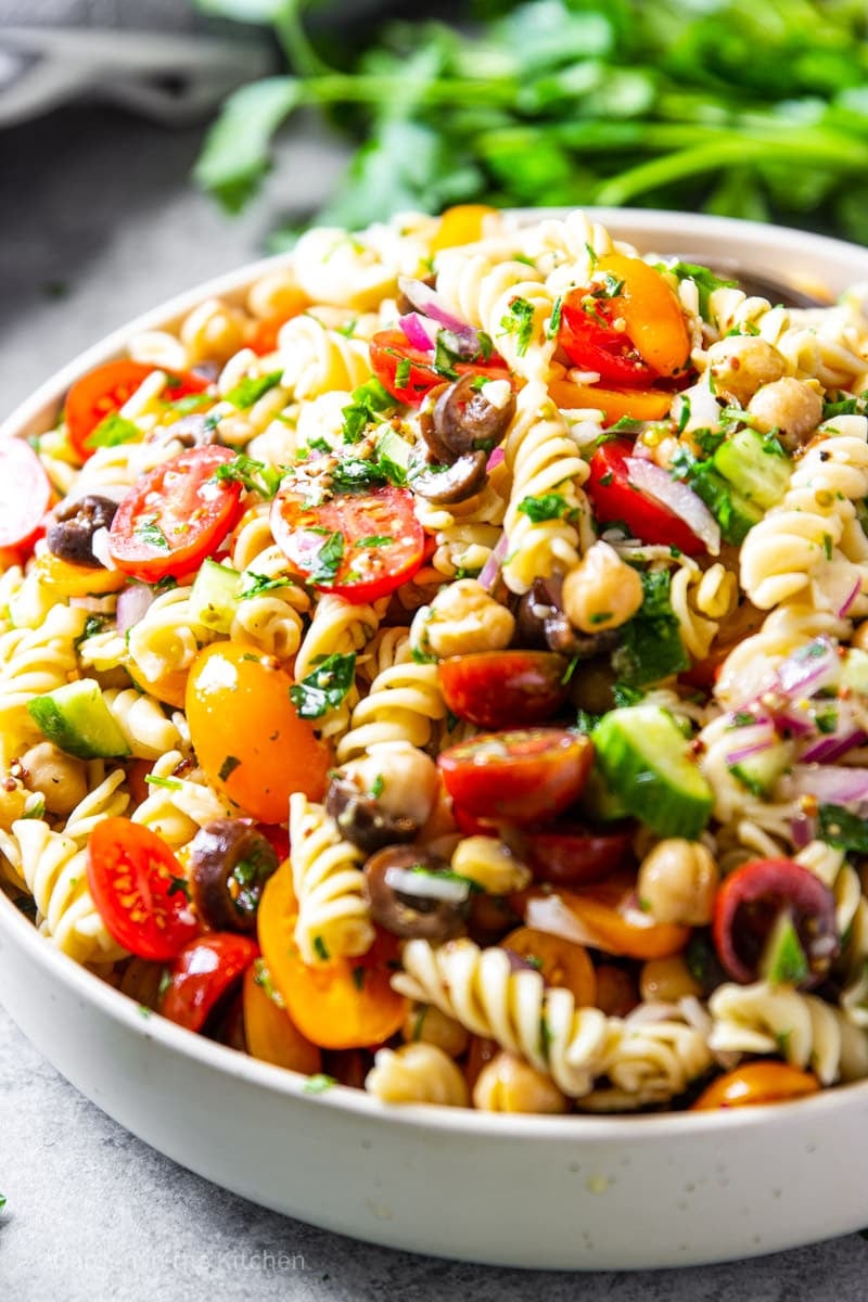 This tasty Mediterranean Chickpea Pasta Salad is chock full of protein for a hearty salad that eats like a meal.  Rotini pasta, chickpeas, cucumbers, black olives, and cherry tomatoes are tossed with an olive oil and lemon juice based dressing for a rainbow of color and flavor. 