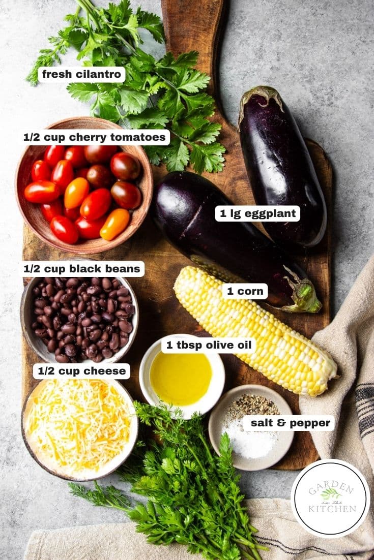Ingredients for eggplant tacos; eggplants, corn, olive oil, black beans, cheese, cherry tomatoes, cilantro, salt and pepper on a wooden cutting board with a white and black tea towel.