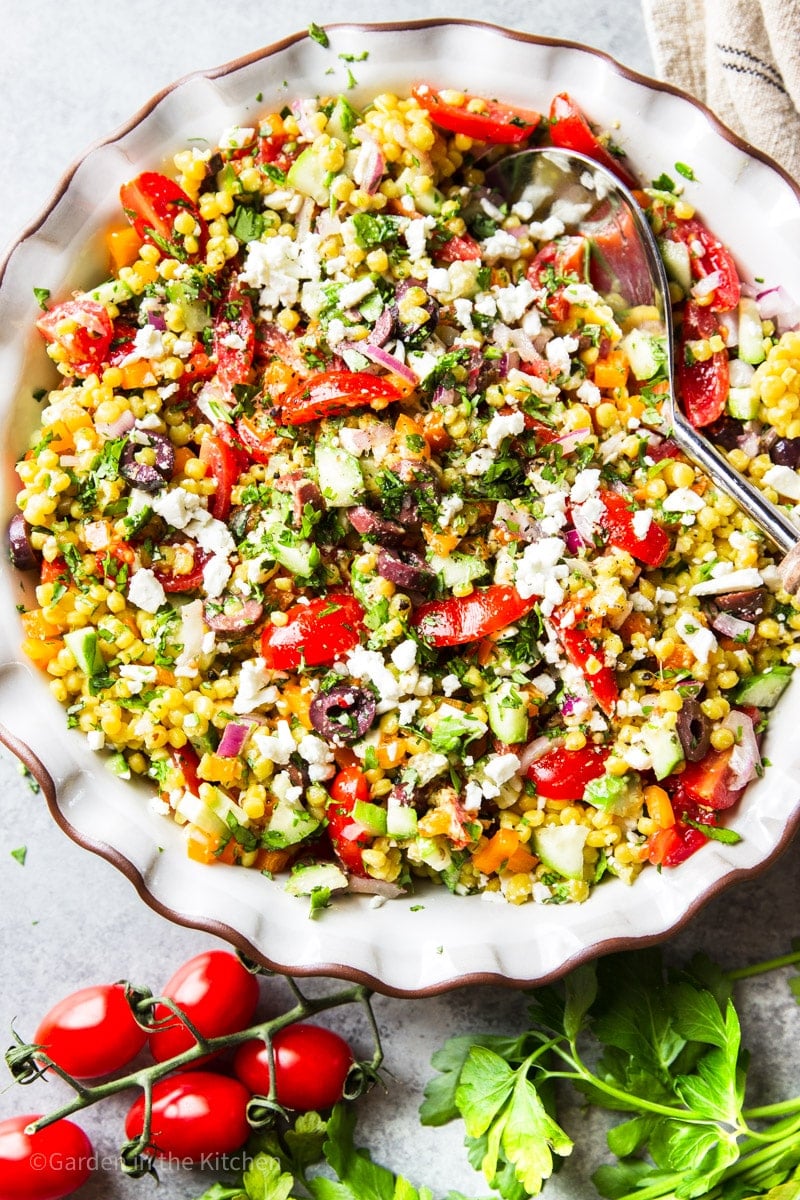 Mediterranean couscous salad served in a bowl with a spoon.