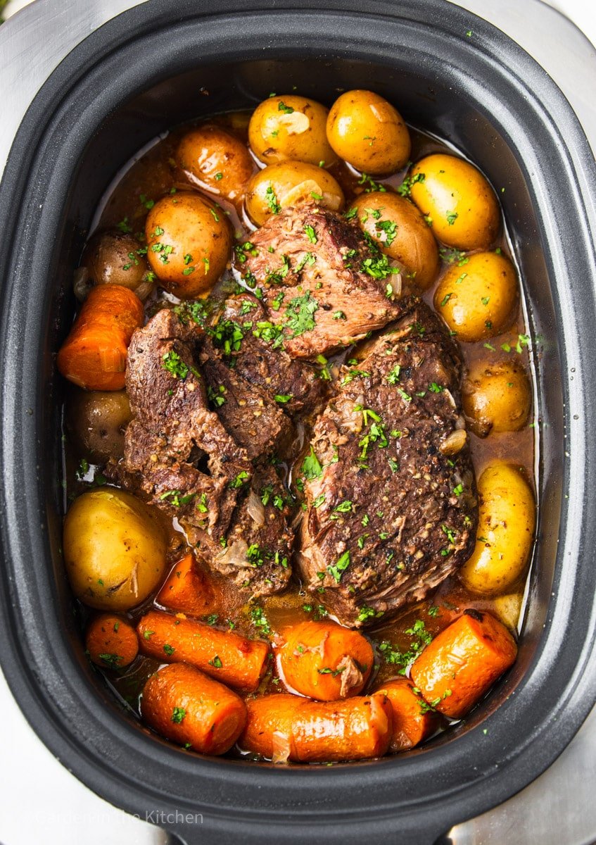 chuck roast in slow cooker with potatoes and carrots. 