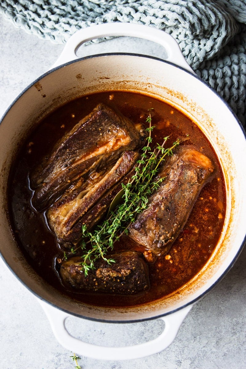 Balsamic glazed short ribs with fresh thyme in a white pot. 