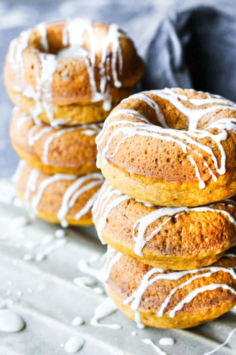 Baked pumpkin donuts with glaze, blue tea towel.