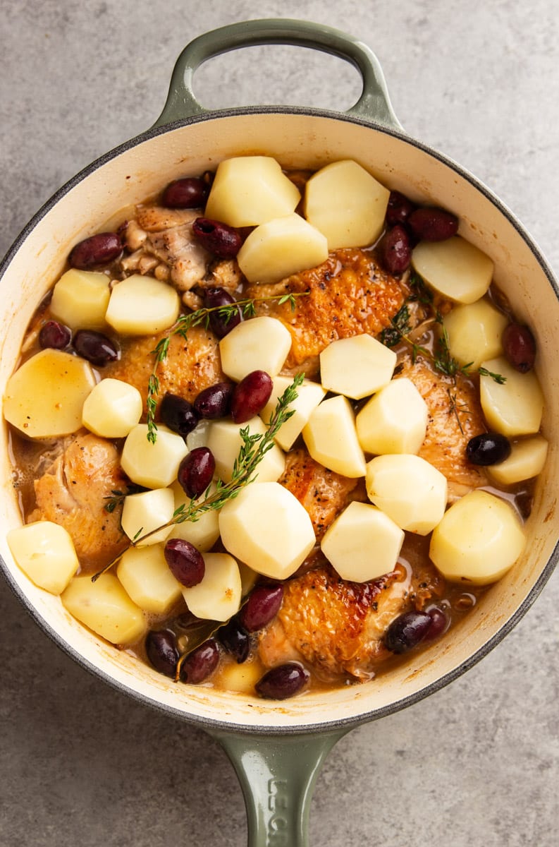 Adding potatoes and olives, to the pot with chicken and mushrooms. 