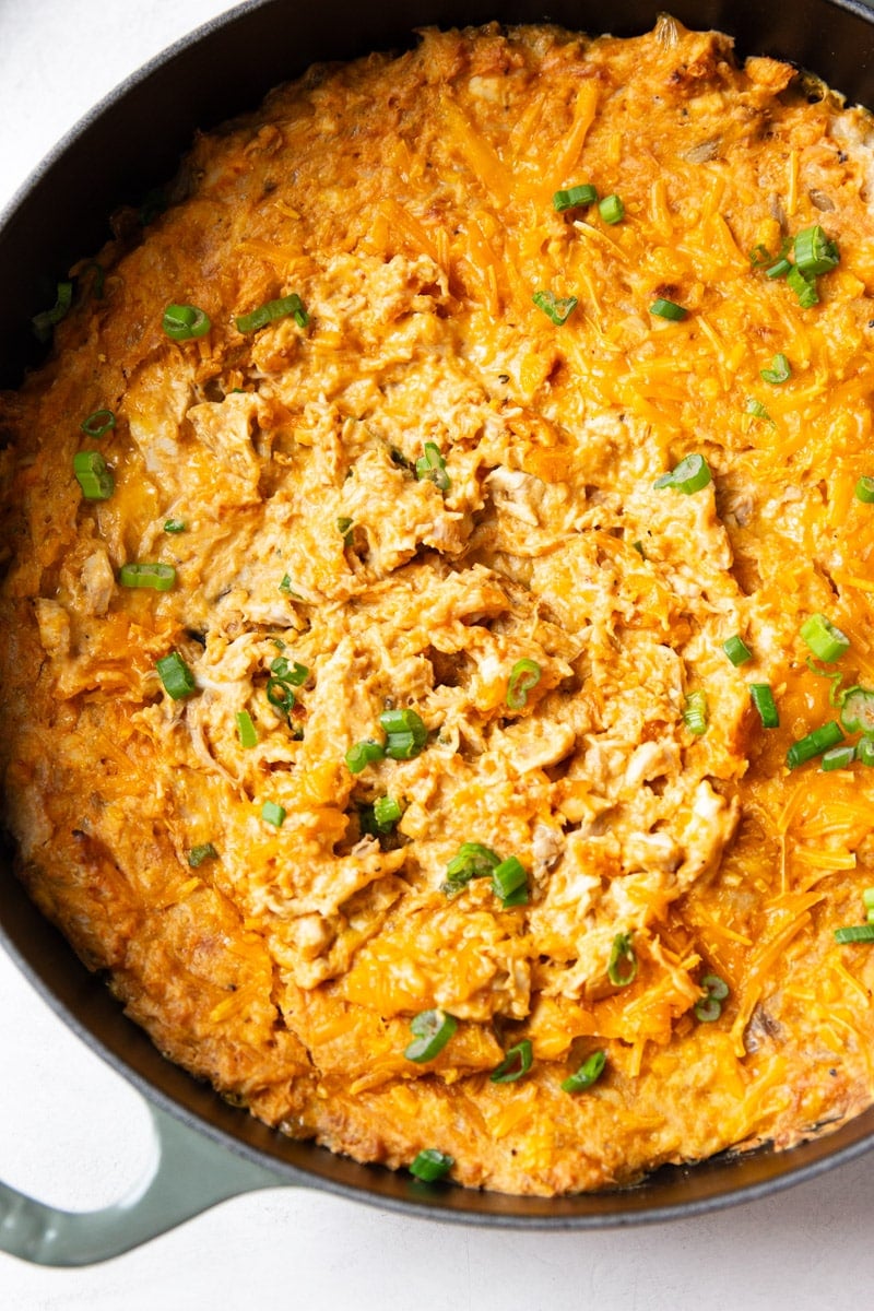 Baked buffalo chicken dip with green onions in a skillet.