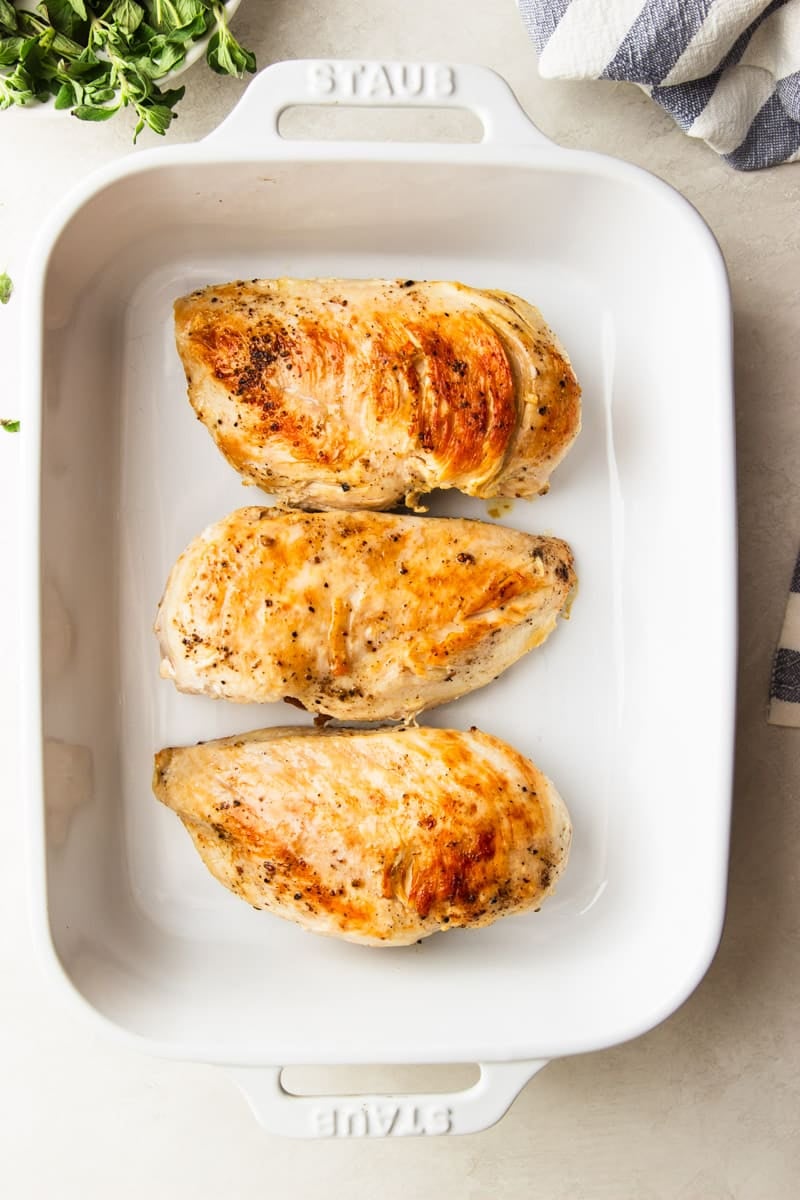 Seared chicken breasts in a baking dish. 