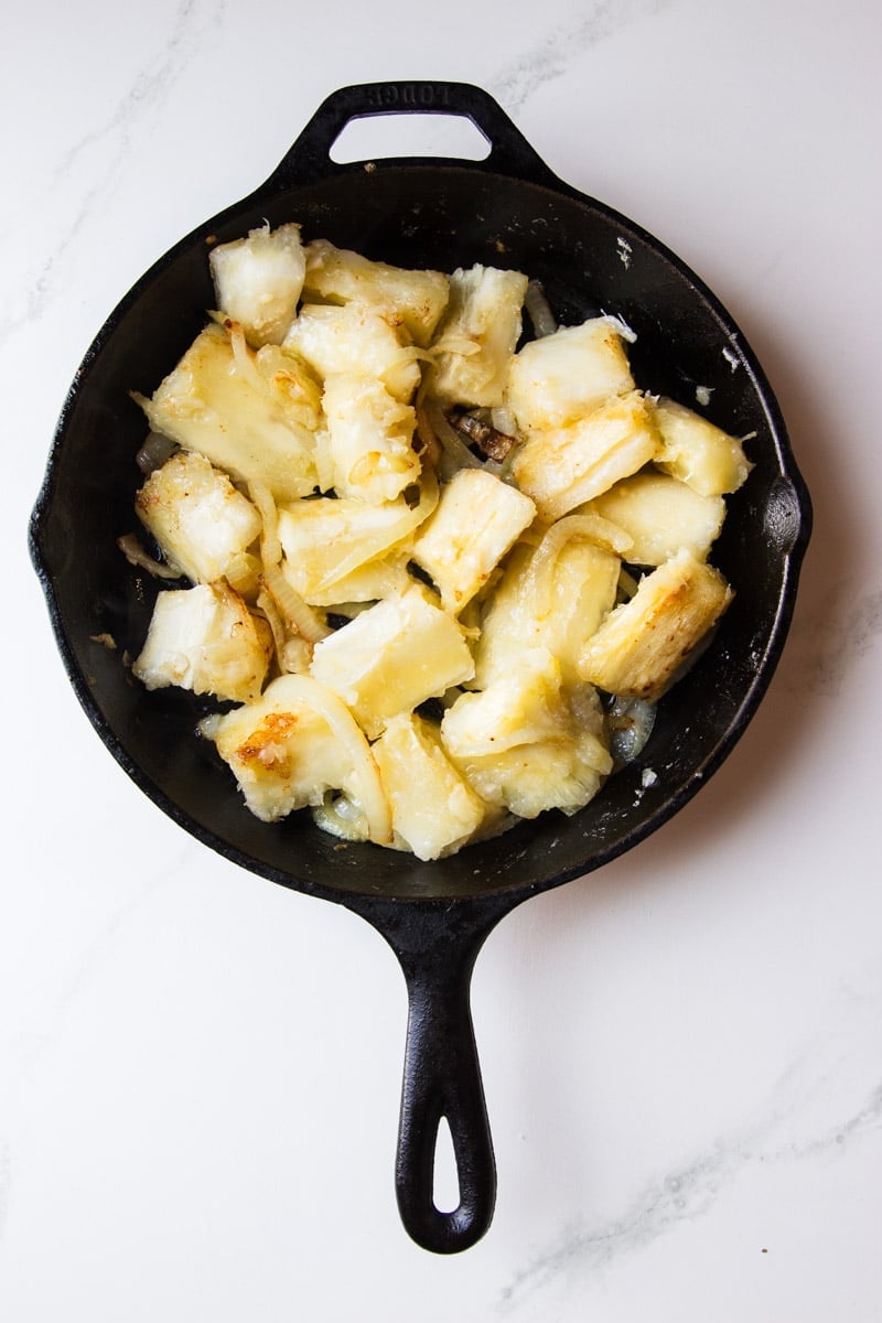 Onion and cooked yuca in a cast iron skillet. 