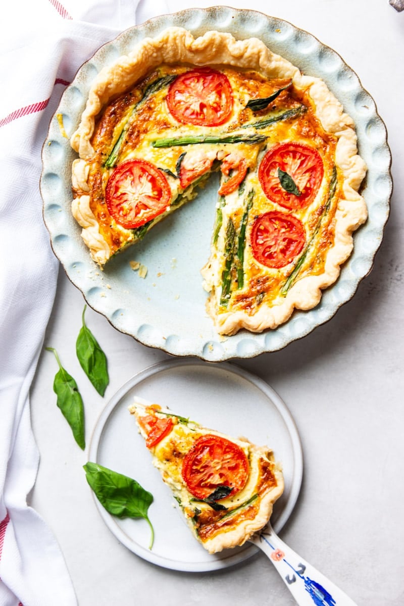 Tomato and asparagus quiche, fresh basil, and a red and white dish towel. 