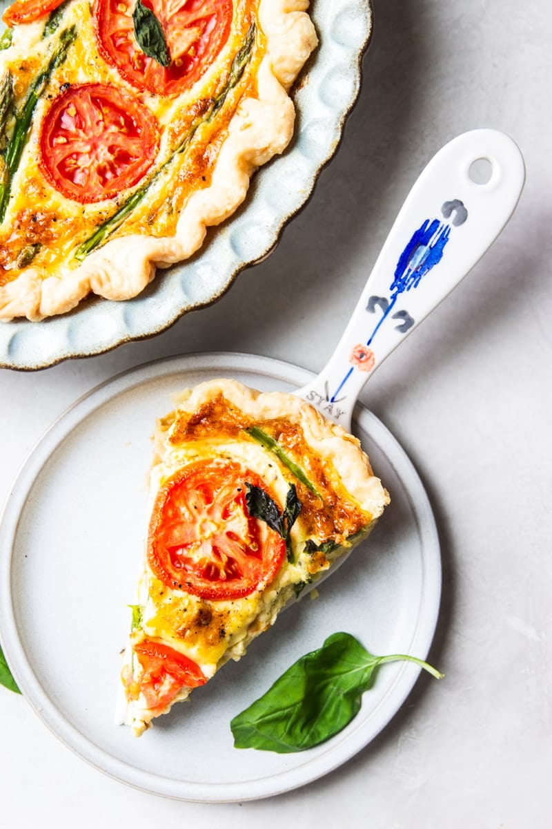 Asparagus and tomato quiche, fresh basil and a colored spoon. 