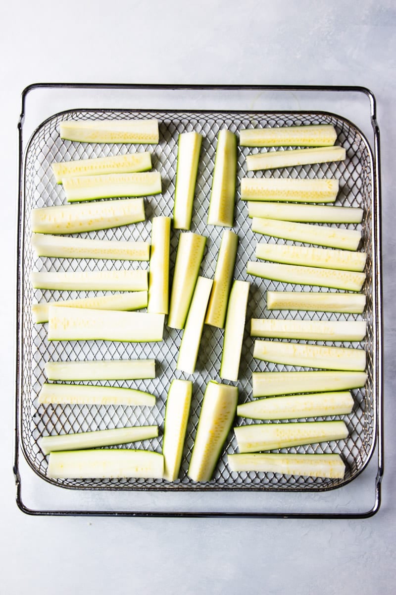 zucchini cut into fries, arranged in an air fryer basket