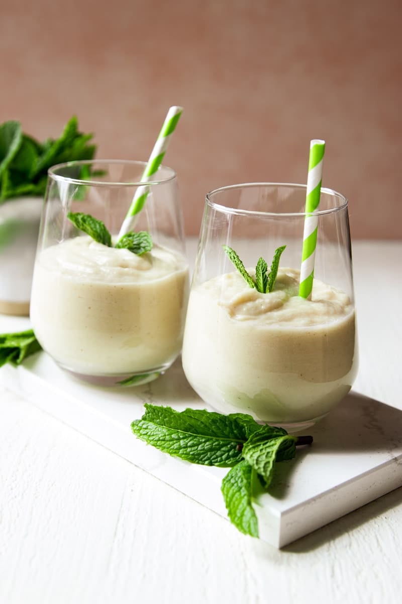 Soursop smoothie, mint leaves, and green and white straws.