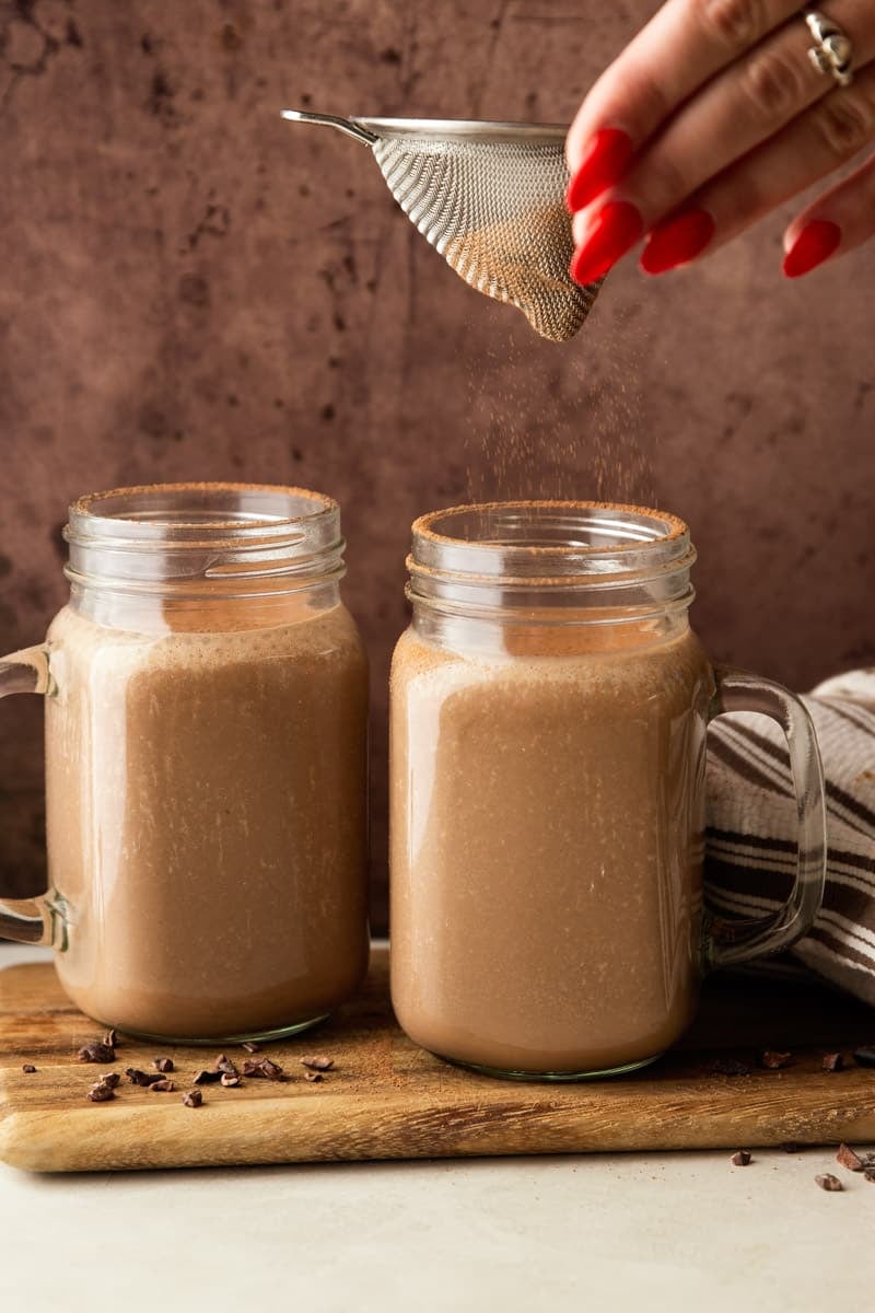 Chocolate Coffee Protein Smoothie in a glass jar on a wooden cutting board, white and brown dish towel. 