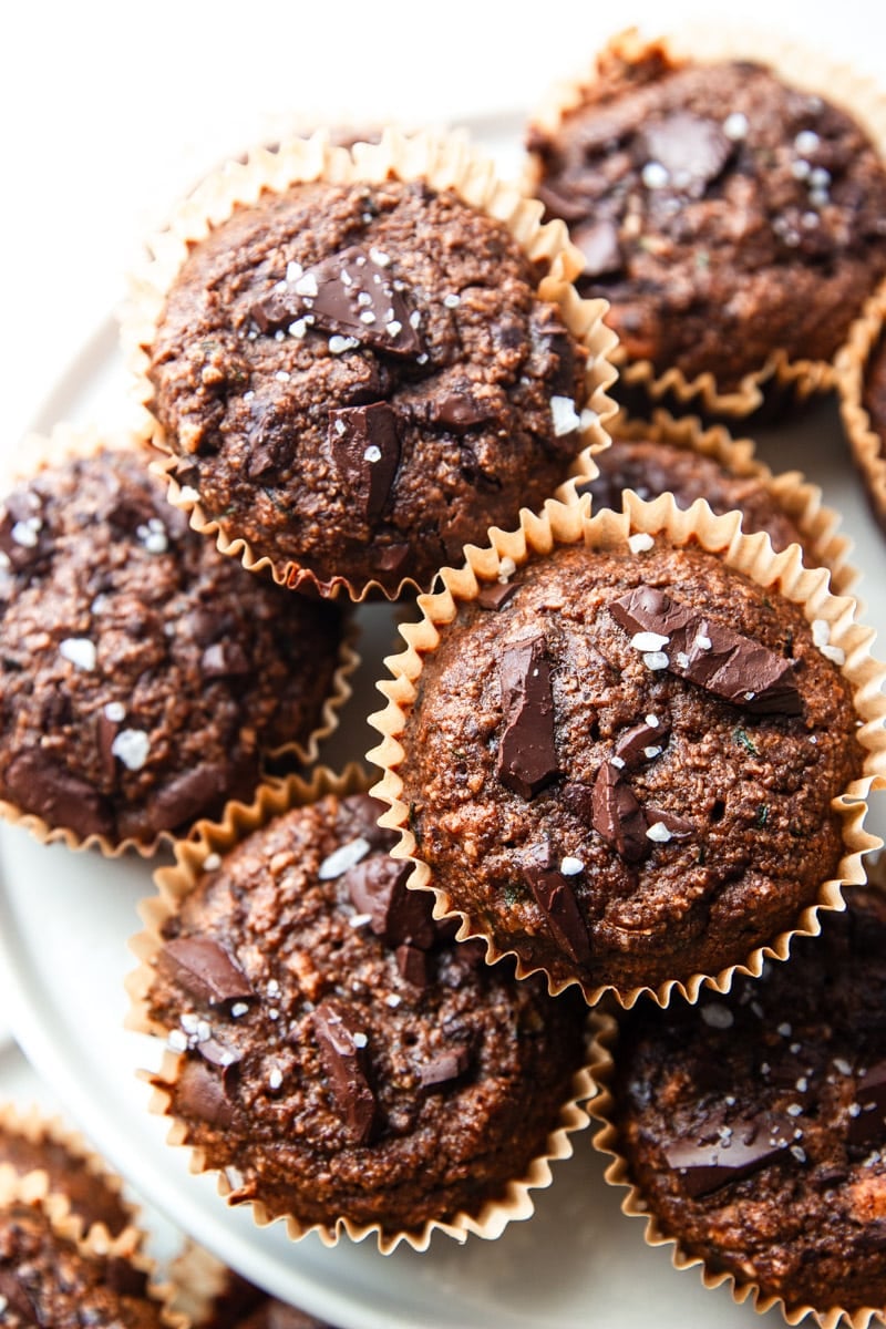 Chocolate zucchini muffins in liners topped with chocolate chunks and sea salt. 