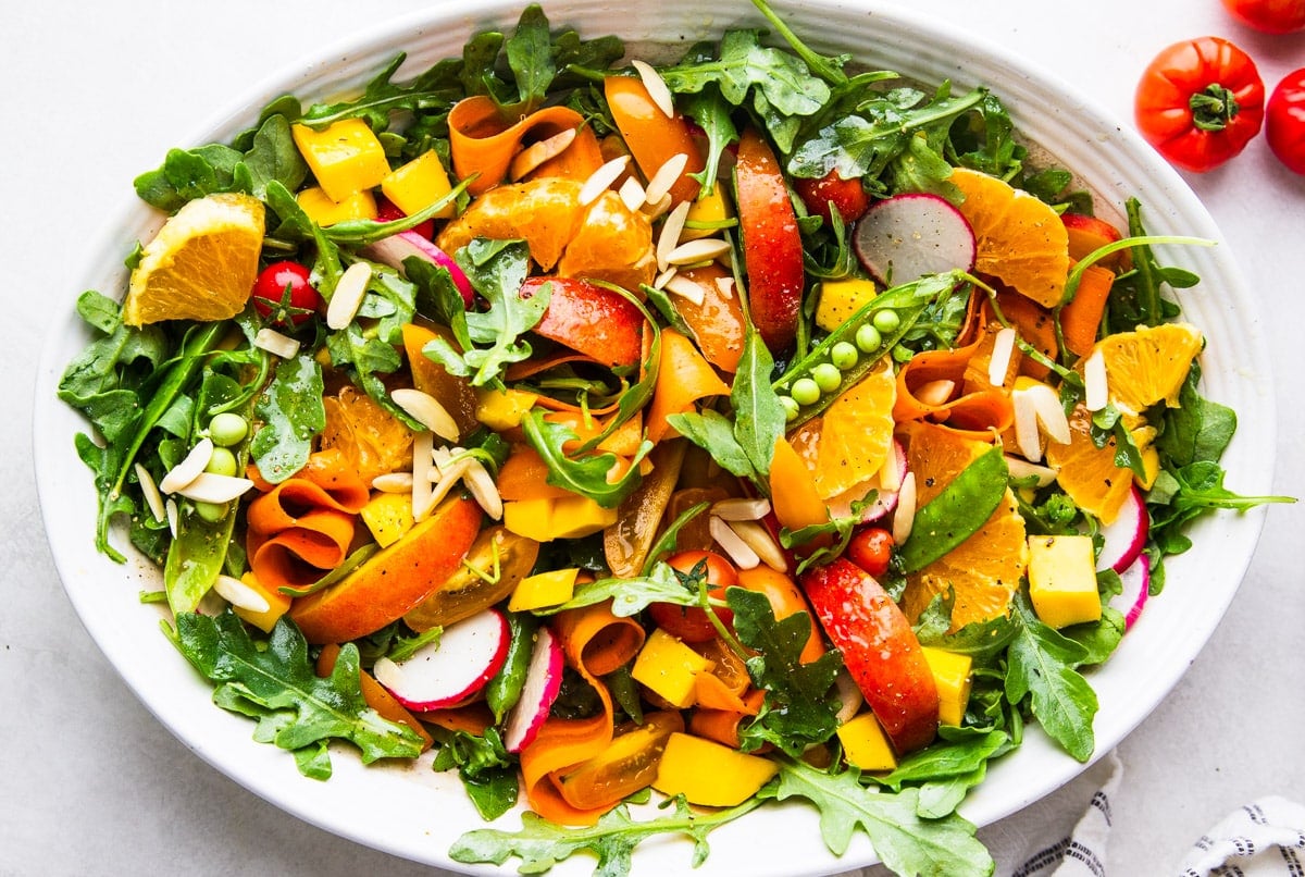 Arugula citrus salad, tomatoes, white and black dish towel. 