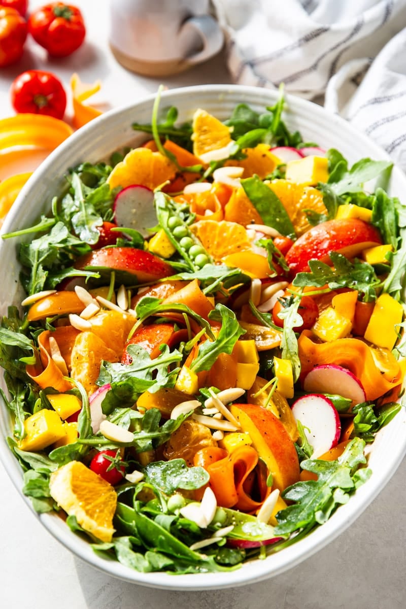 Tomatoes, white and black dish towel, arugula and citrus salad. 