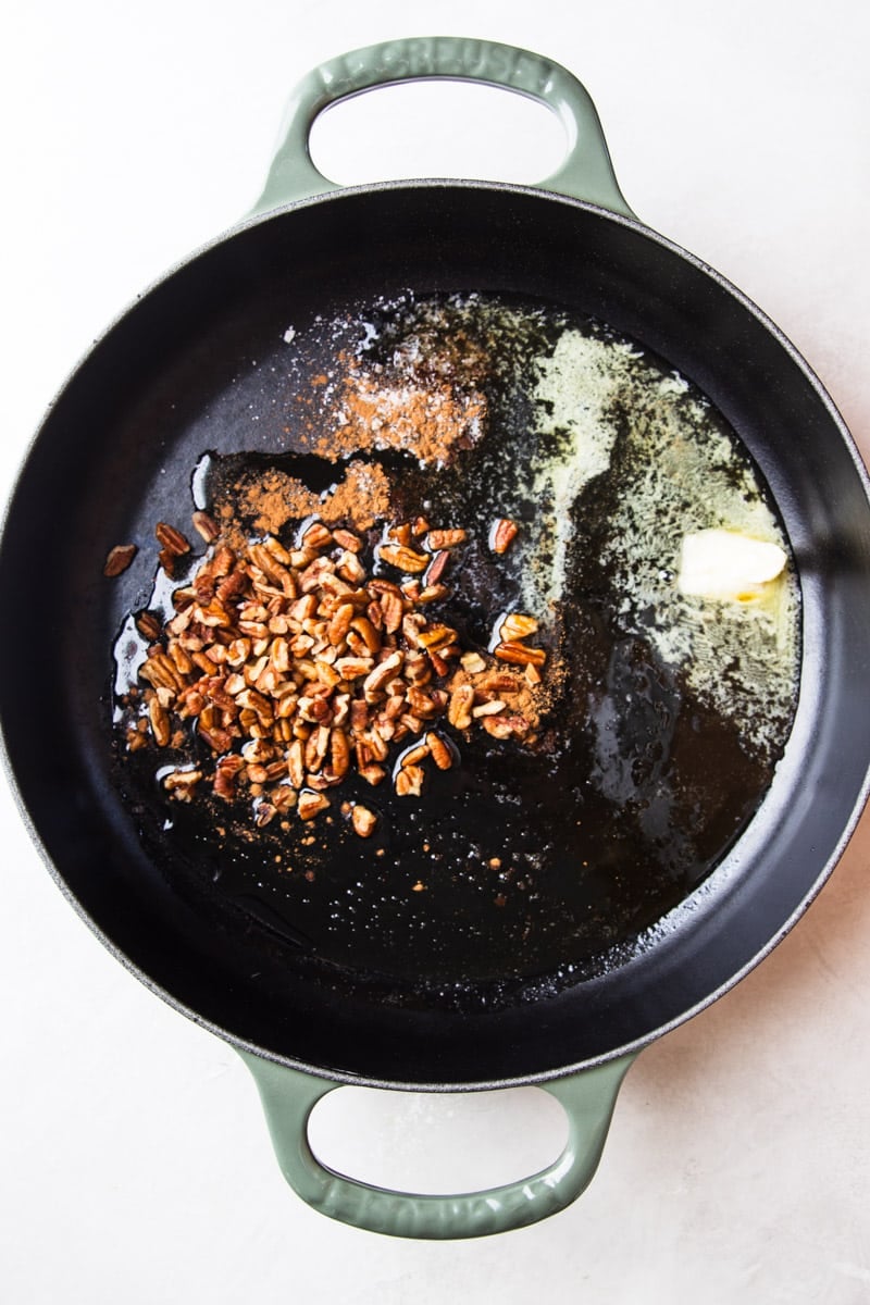 Pecans in a skillet with butter and maple syrup. 