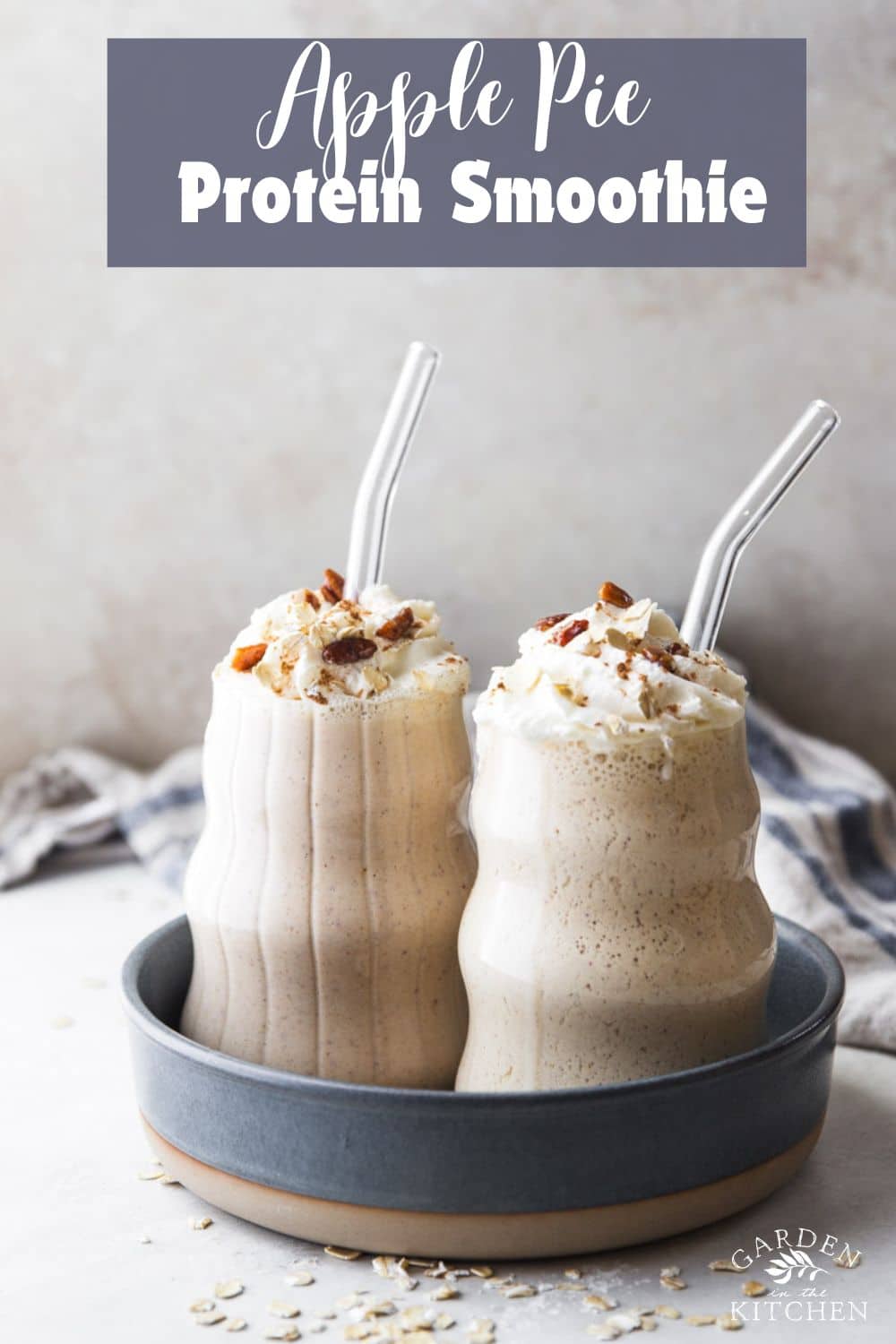 Apple pie protein smoothies with glass straws, cinnamon sticks, oats, blue and white dish towel.