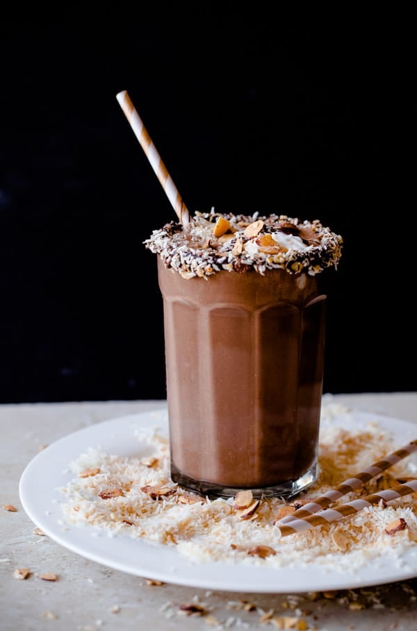 Almond Joy Smoothie, coconut flakes, white and brown straw, white plate. 