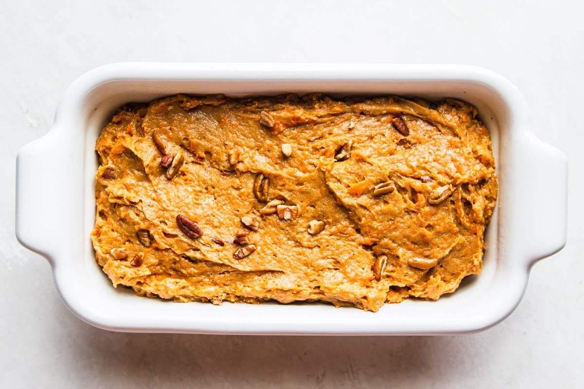 Sweet potato bread with pecans in a white loaf pan.