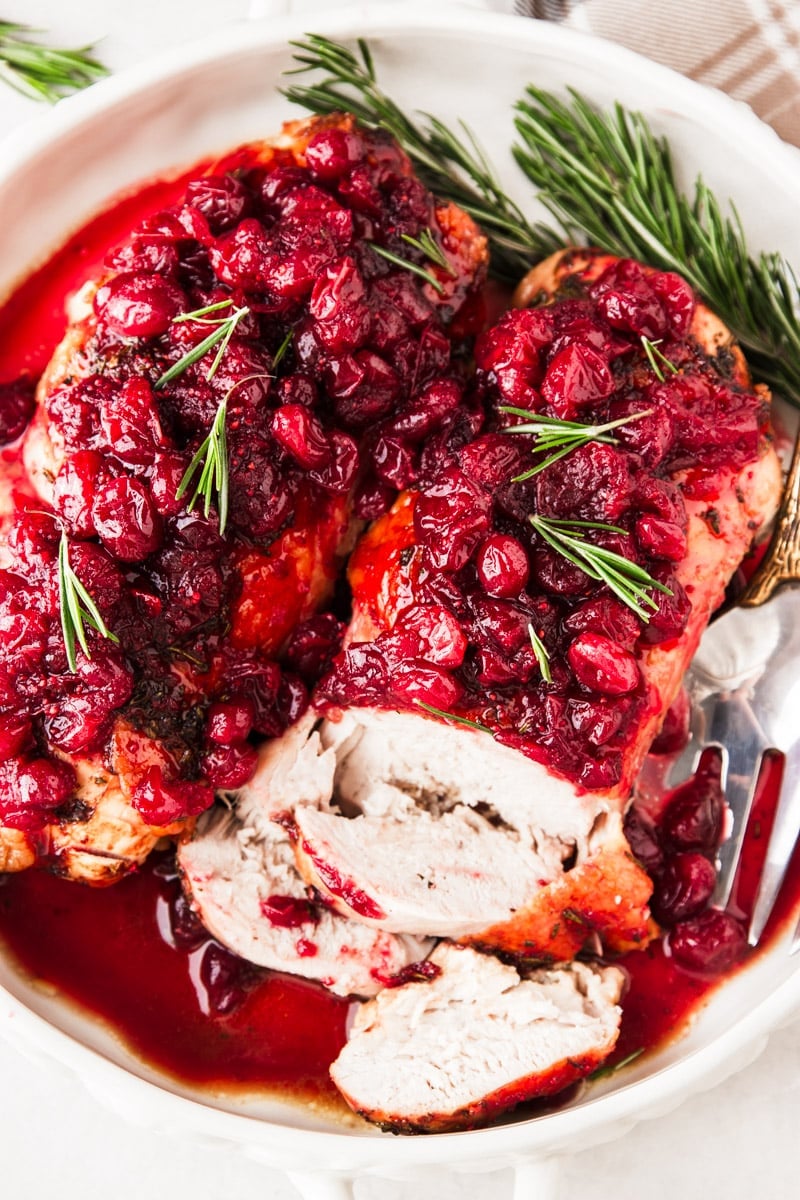 Plaid dish towel, cranberries, fresh rosemary, cranberry glazed turkey breasts.