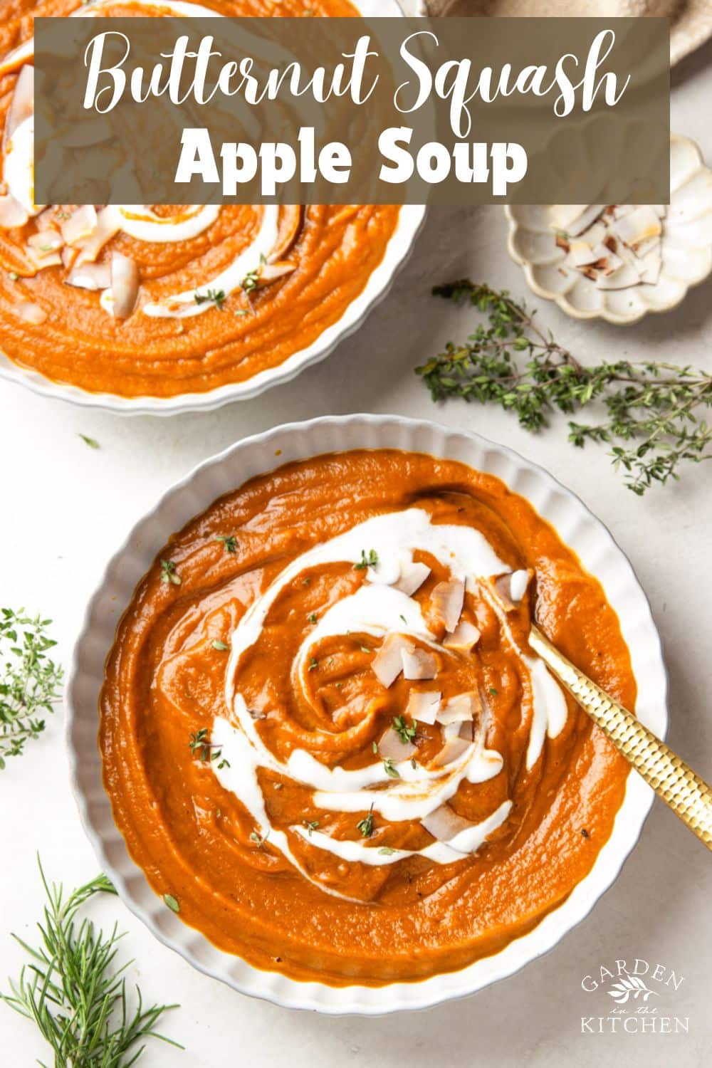 Butternut squash apple soup drizzled with yogurt and topped with coconut chips in white bowls, a white bowl of coconut chips, and fresh thyme.