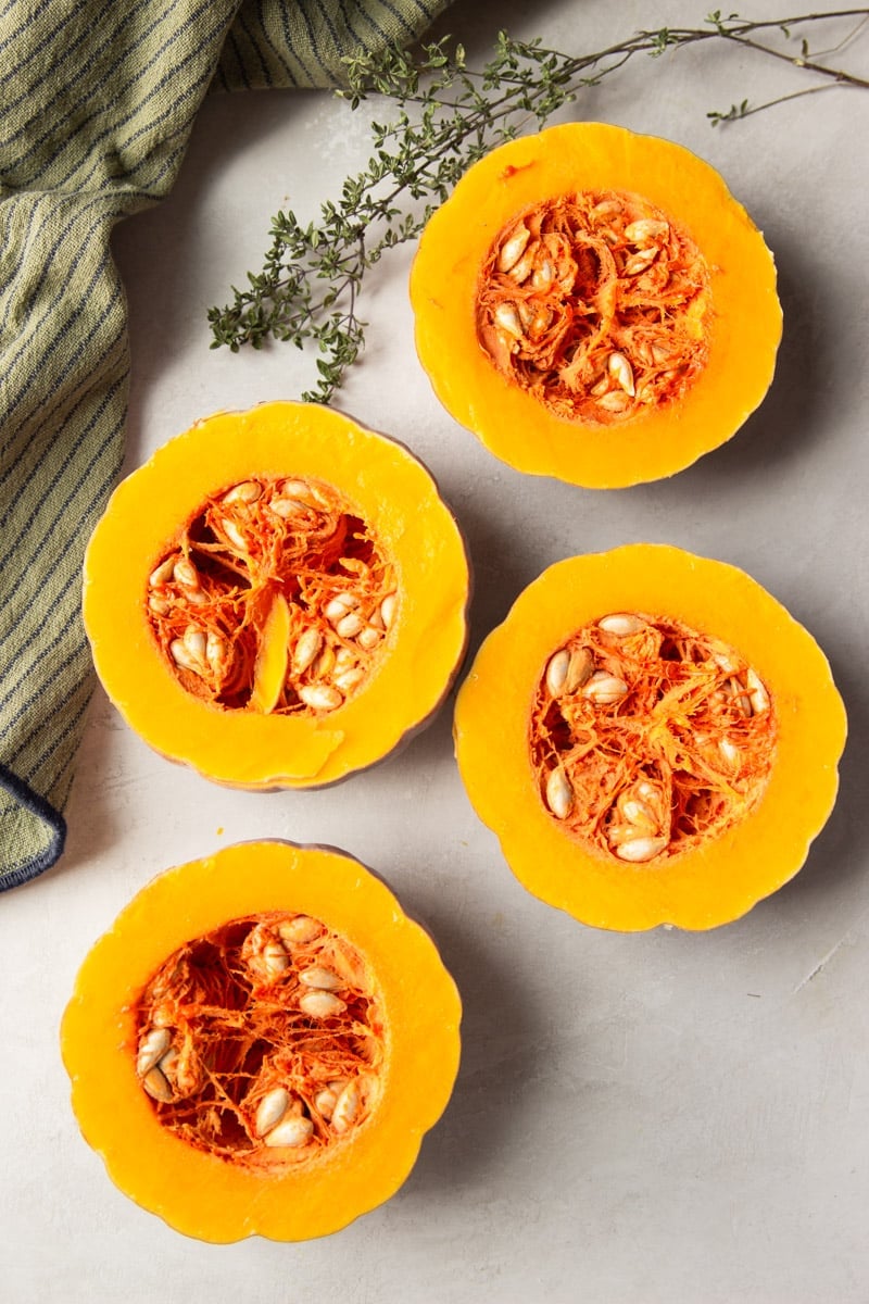 Koginut squash cut in half, striped dish towel and fresh thyme. 