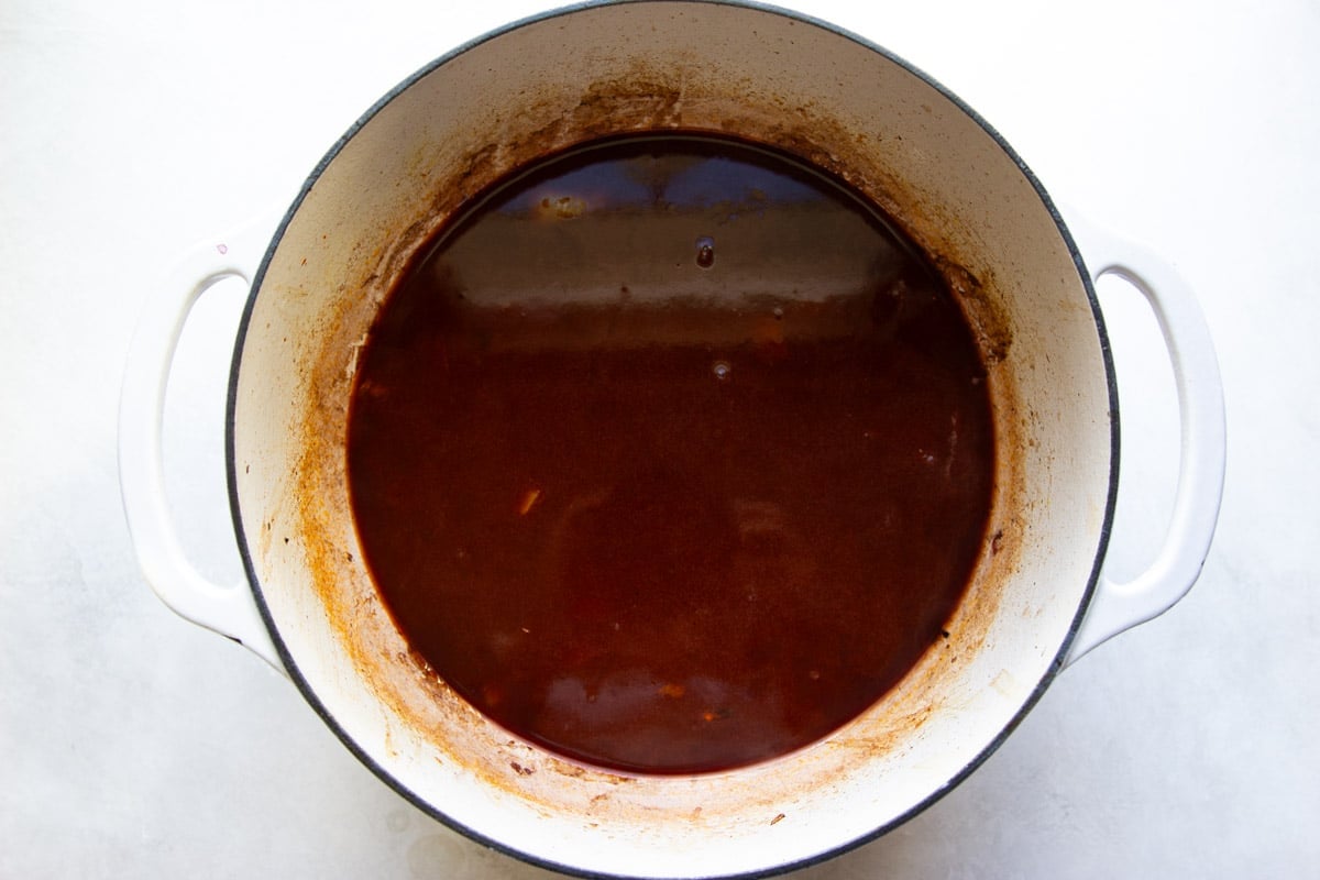 Wine and broth in a white Dutch oven. 