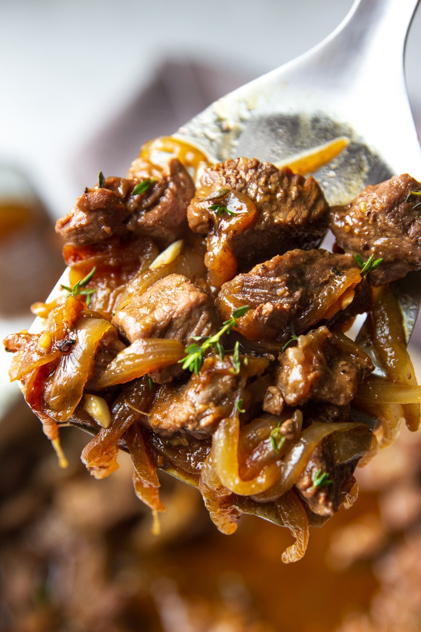 close up of steak bites with caramelized onion with a spatula