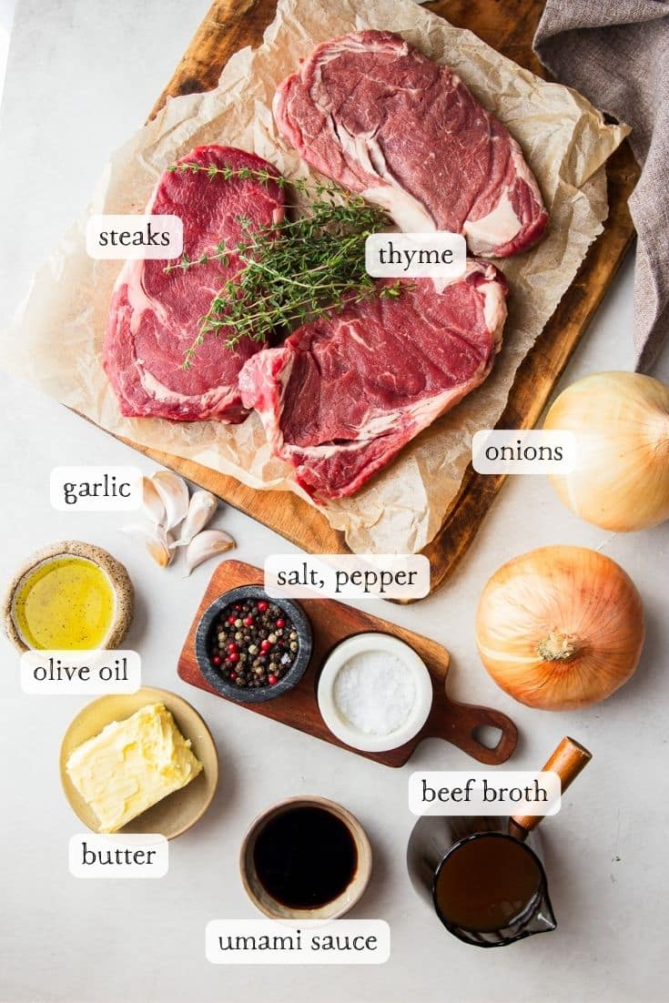 Ingredients for steak bites; rib eye steaks, thyme, onions, oil, butter, salt and pepper, umami sauce and beef broth