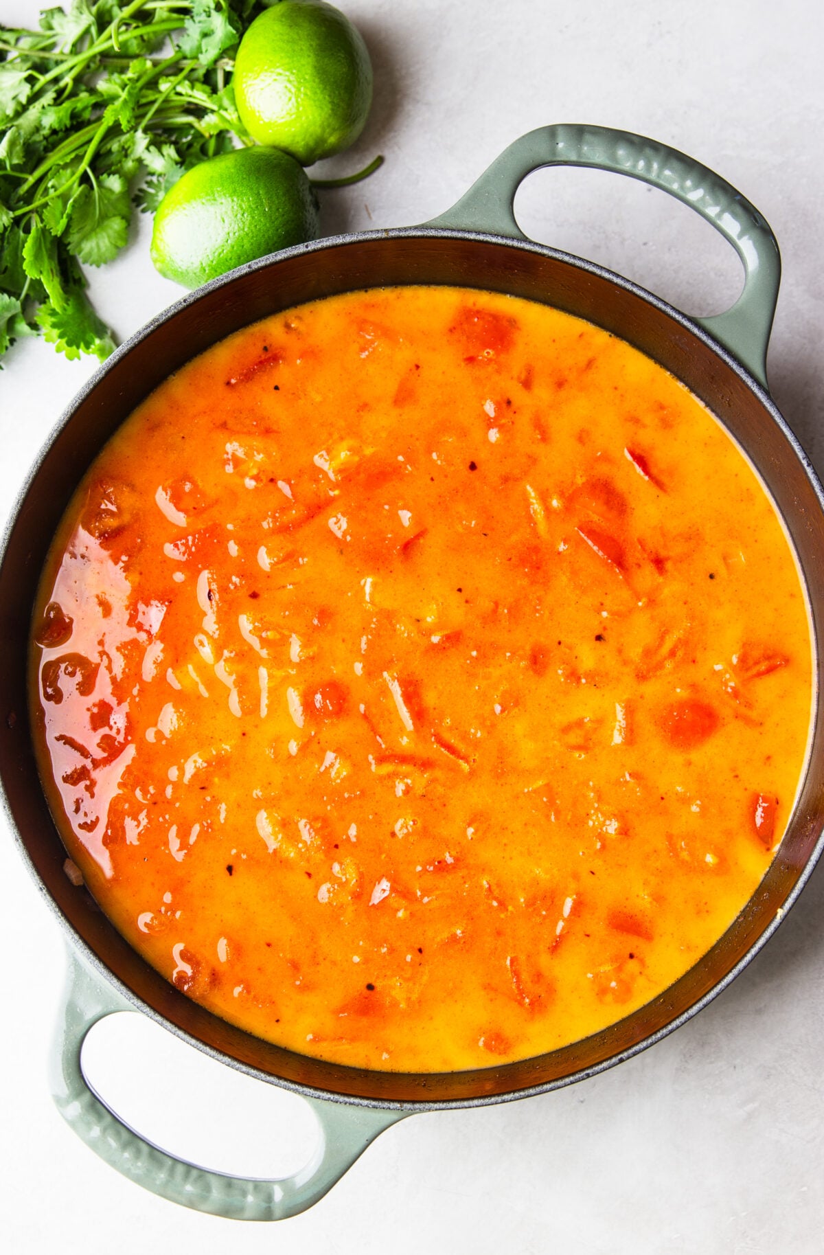 skillet with sautéed onions and tomato in broth