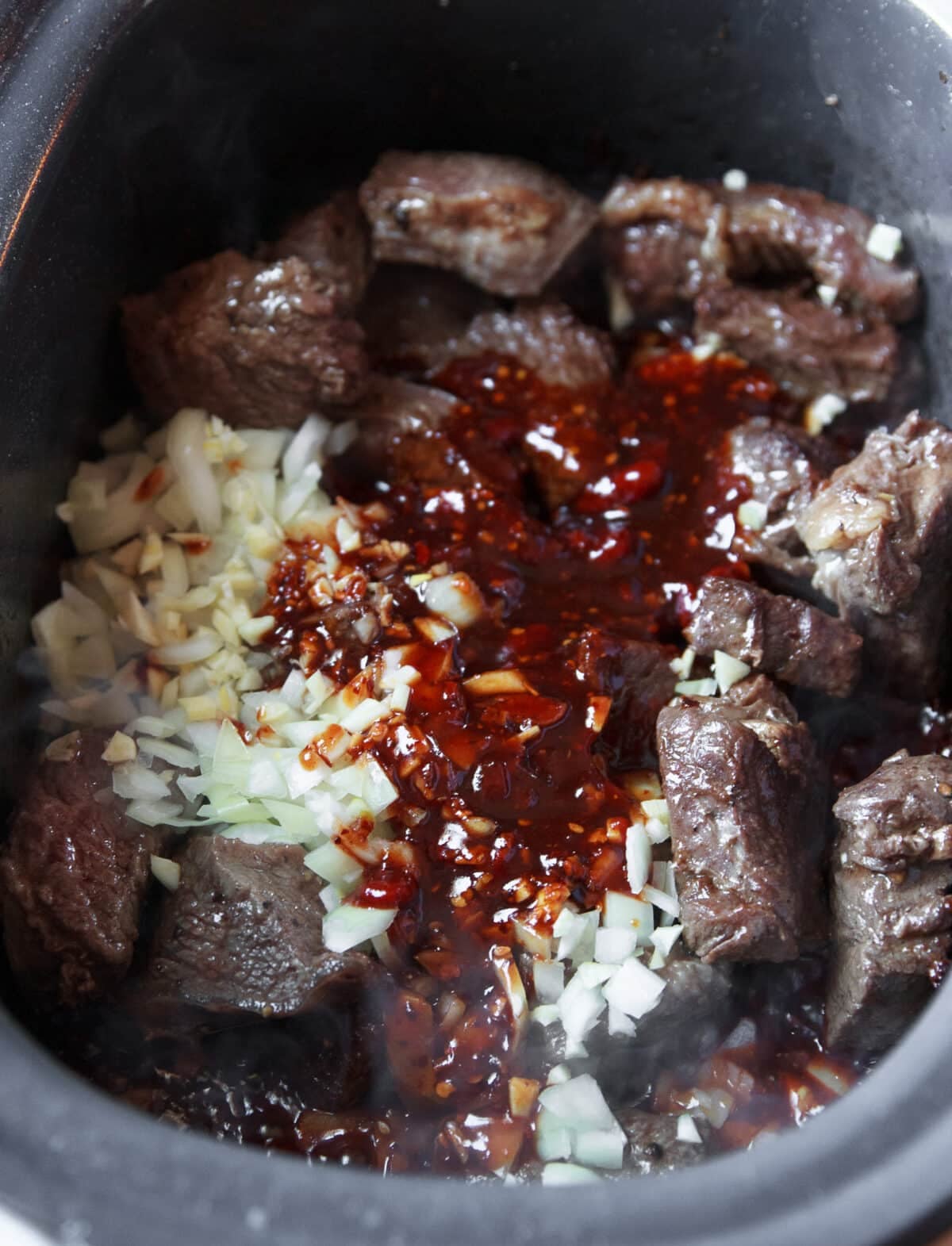 Slow Cooker Hot Honey Chili Beef made with tender beef chuck, chili crunch, garlic, and a rich sweet-spicy sauce. Easy to make and perfect over rice.