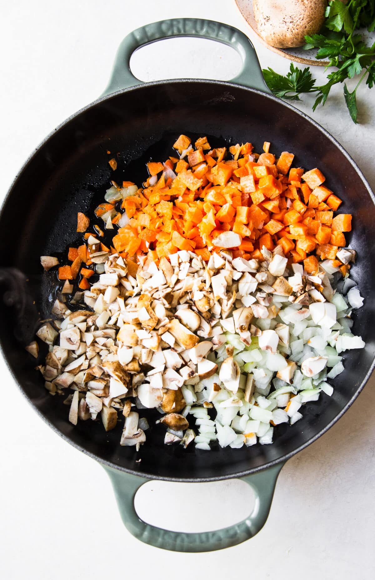 carrots, mushrooms and onions sautéing in a skillet